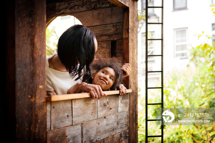 Girl (8-9) relaxing with mother in tree house