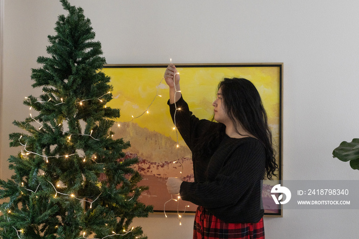 Asian American trans woman decorating for the holidays.