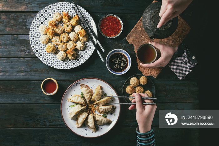 Overhead view of hands reaching for Dim sum Gyozas and pouring tea