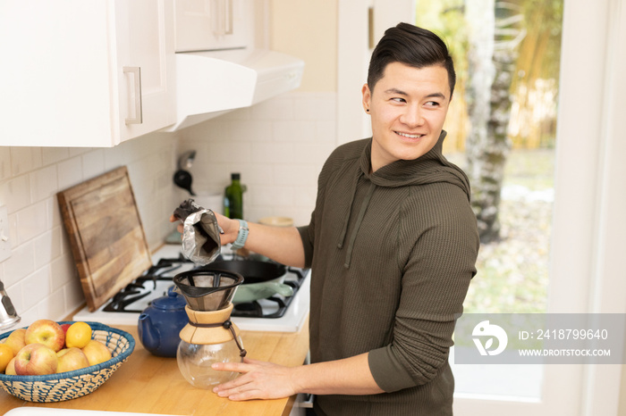 Chinese American man prepares coffee in the kitchen.