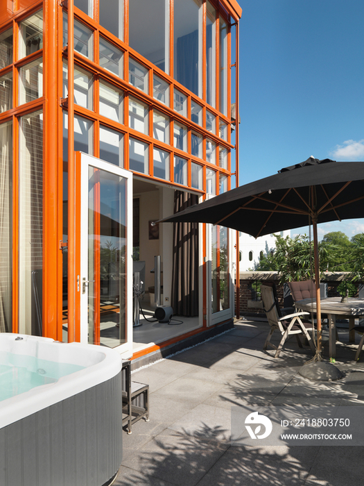 Outdoor furniture with patio canopy by apartment against blue sky