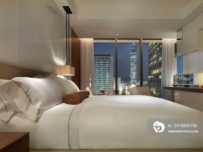 Contemporary hotel bedroom with city view at night