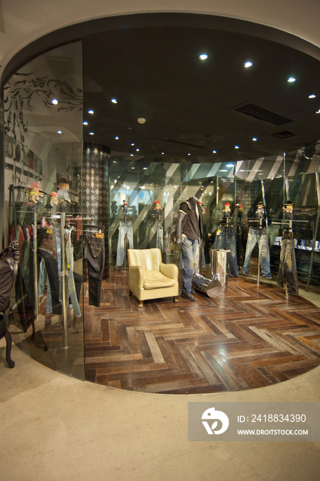 Mannequin displayed by armchair in contemporary clothing store