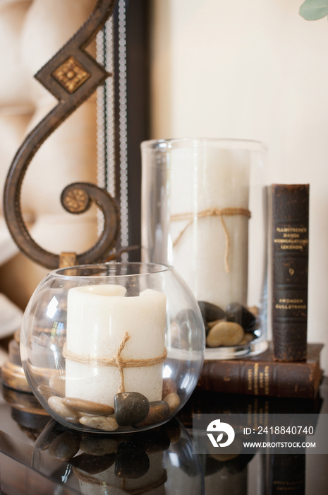 Close-up of lamp stand with candles; and books on console table at home