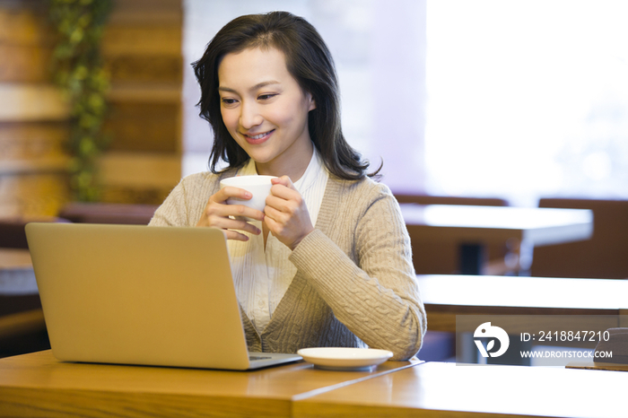 年轻女子在咖啡馆用笔记本电脑