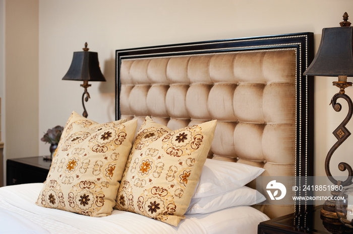 Close-up of throw pillows on bed with lamp on side table in bedroom at home