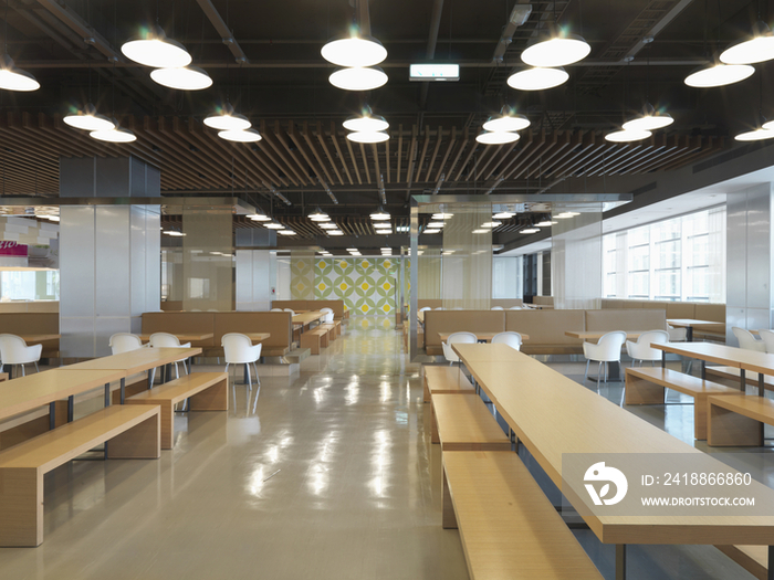 Ceiling lights over wooden benches and empty tables along hallway in the restaurant