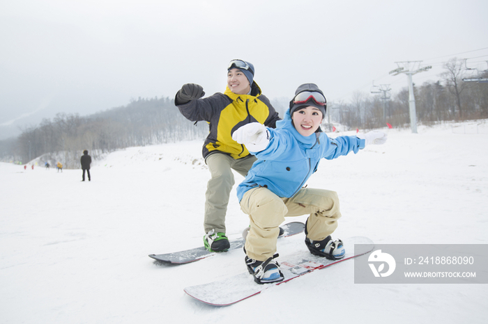 年轻情侣一起单板滑雪