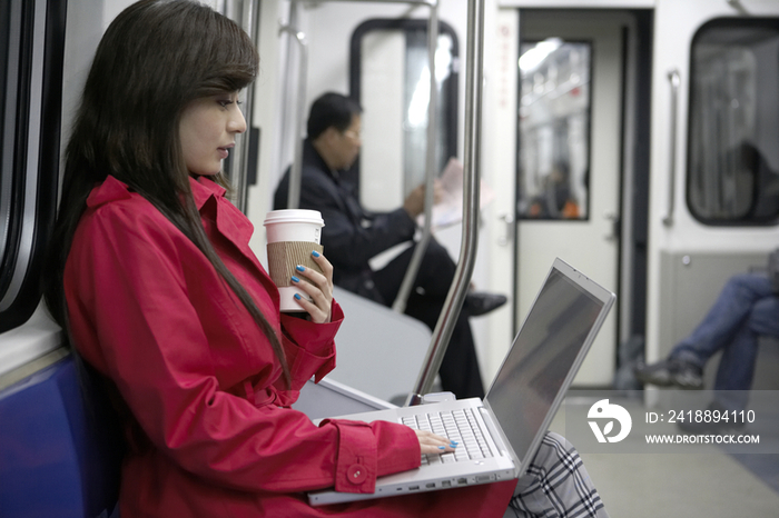 年轻女子在地铁里用电脑