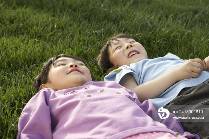 小男孩和小女孩躺在草地上