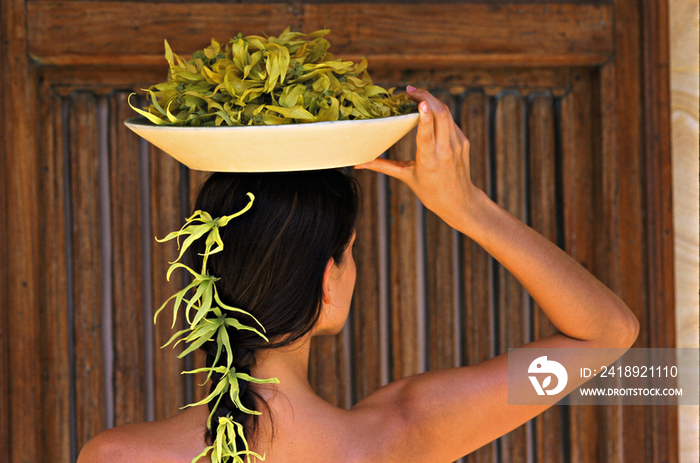 Woman carrying bowl with ylang ylang on her head