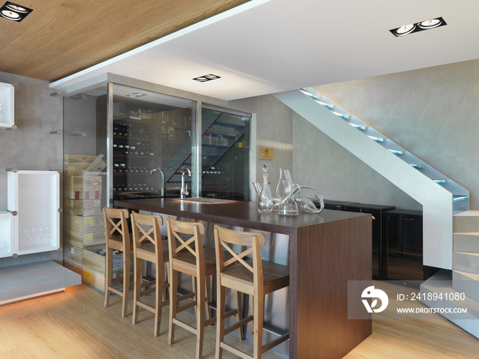 Alcohol bottles in glass rack with wooden stools at bar counter in the house; Scottsdale; USA