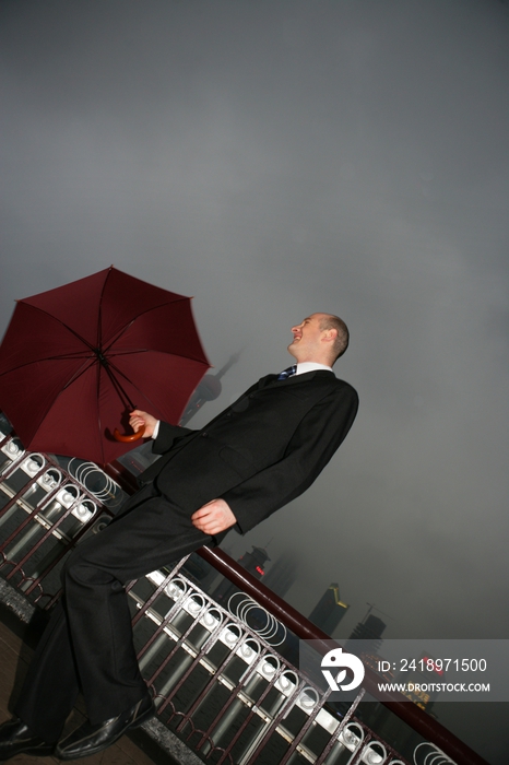 阴雨天外滩黄浦江边一位外国商务人士拿伞跳跃