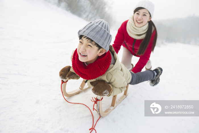 母子俩在雪地上玩雪橇