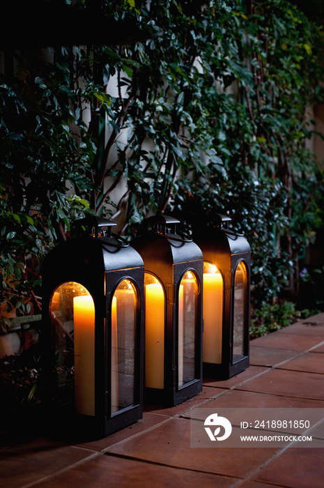 Close-up of empty lanterns in a row on tiled floor by plants