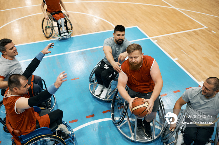 Basketball player in wheelchair trying to pass through his opponents while playing match on the court.