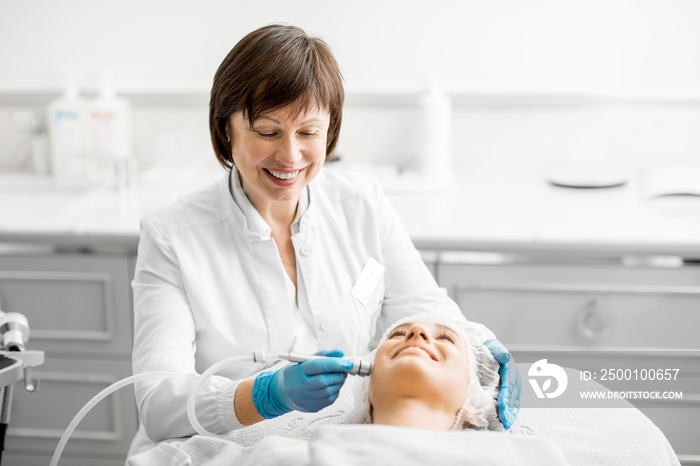 Senior woman cosmetologist making facial procedure to a young client in a luxury medical resort office