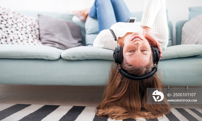 Woman with headphones on sofa at home listening music