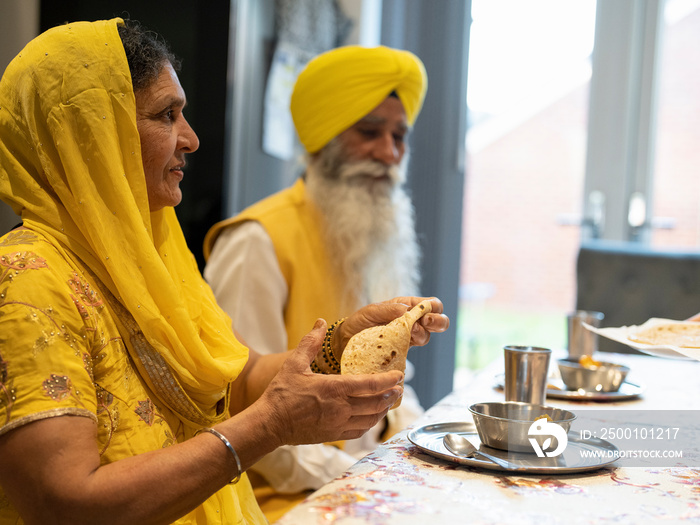 Couple in traditional clothing eating meal at home