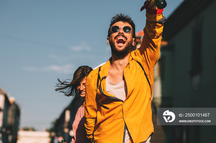 Young couple dancing on the street and holding two bottles of beer