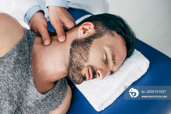 chiropractor massaging neck of handsome man lying on Massage Table