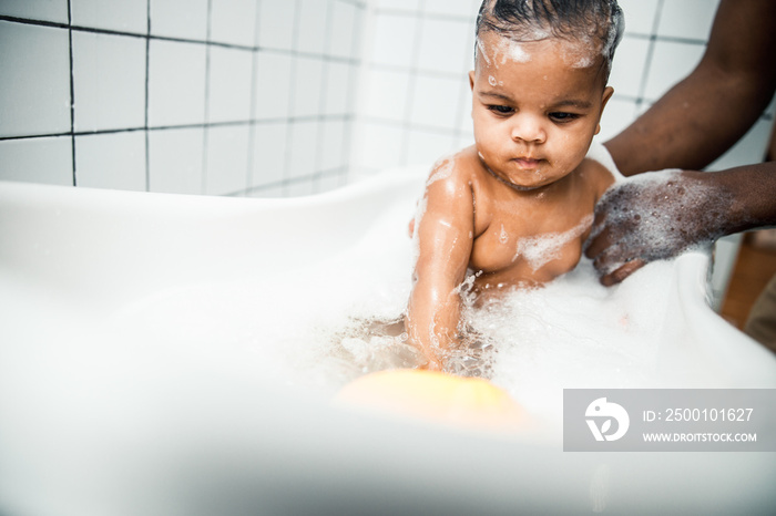 Adorable toddler baby taking bath in bathroom