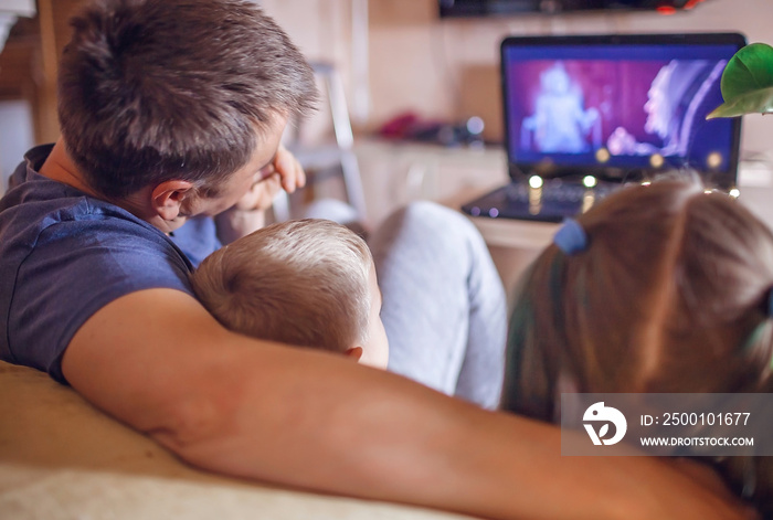 Family movie night. Father with kids watching movie with popcorn by laptop, indoor lifestyle