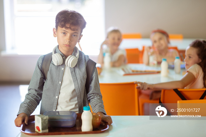 Dark-haired boy feeling like outcast while eating alone in canteen