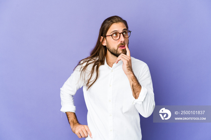 Young man with long hair look looking sideways with doubtful and skeptical expression.