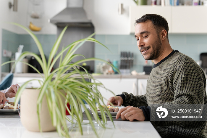 Smiling mature man eating breakfast at home