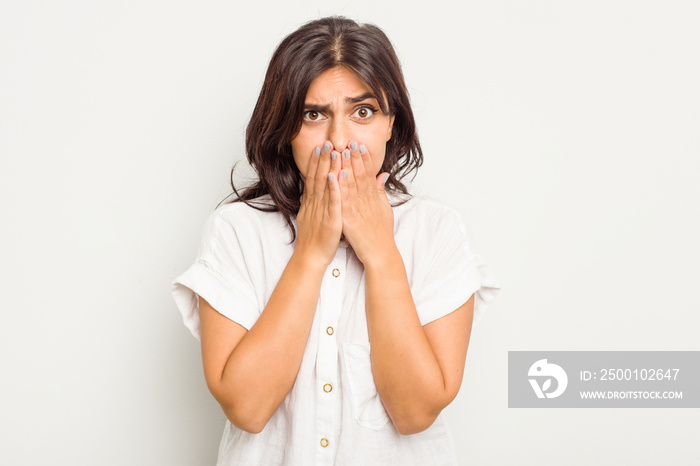 Young Indian woman isolated on white background covering mouth with hands looking worried.