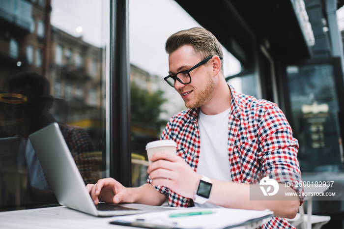 Successful remote worker watching laptop in summer cafe