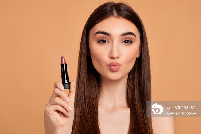 young happy positive woman holding pink lipstick