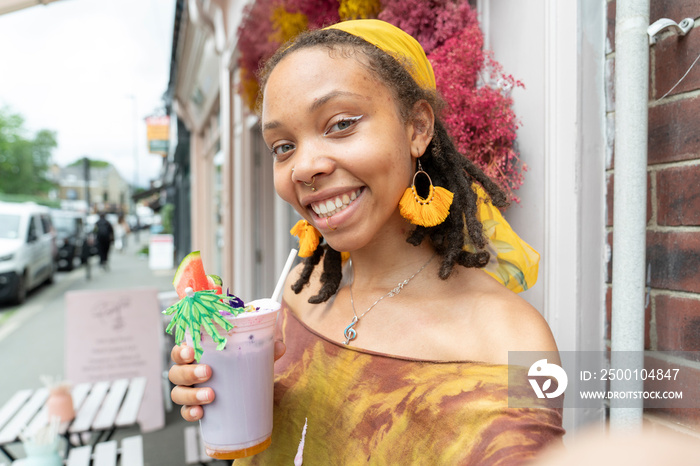 Portrait of young woman drinking smoothie in city