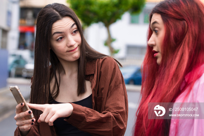 angry young girls looking at mobile phone