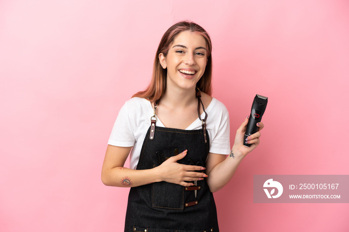 Young hairdresser woman isolated on pink background smiling a lot