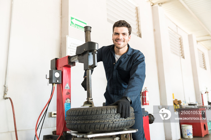 Serviceman In Uniform Using Tire Changer At Garage