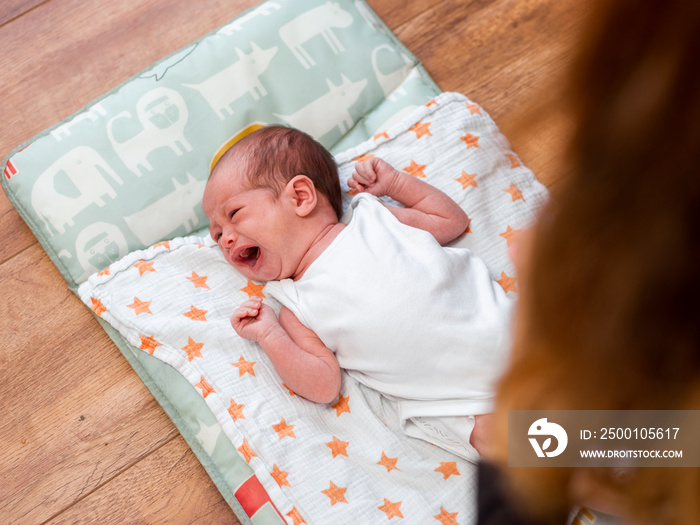 Crying infant girl   lying on blanket