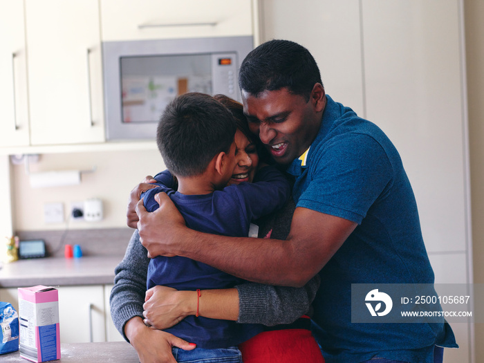 Parents and son hugging in kitchen