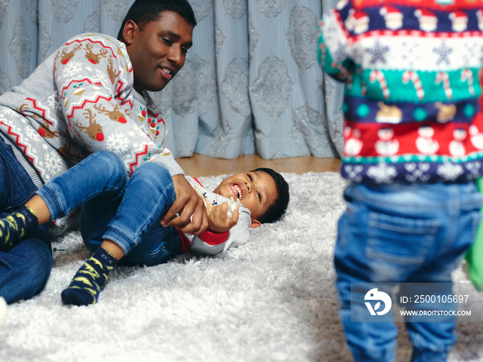 Father and son playing on living room carpet