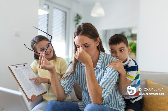 Upset mother having problem with noisy naughty daughter and son jumping on couch and screaming, demanding attention, frustrated mum tired of difficult child trying to work from home