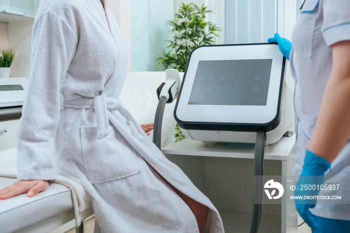 Partial view of cosmetologist in rubber gloves touching laser machine in clinic