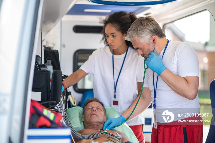 Paramedical staff examining the sick man in the ambulance vehicle