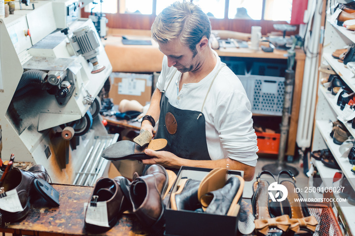 Shoemaker with shoes to repair on a rack in his workshop