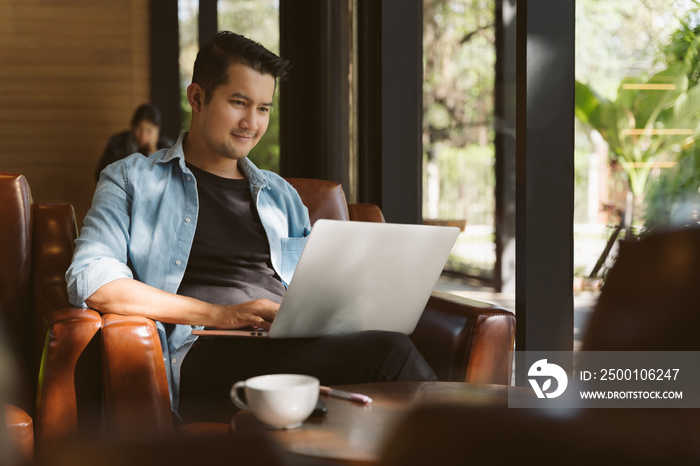 A freelancer bearded man in t-shirt taking notes at laptop in cafe. Freelance and remote work. Concept of freelance and financial freedom.