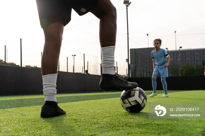 Man and girl (6-7) playing soccer on soccer field