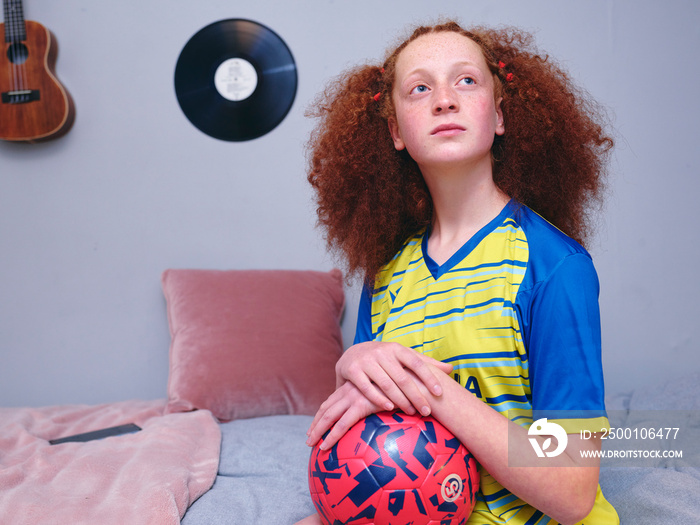 Girl in sports clothing sitting on bed