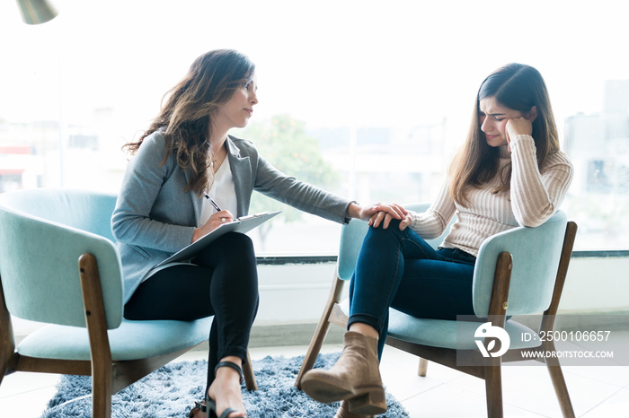 Therapist Giving Support To Crying Female Patient In Office