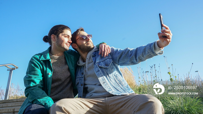 Smiling gay couple taking selfie outdoors