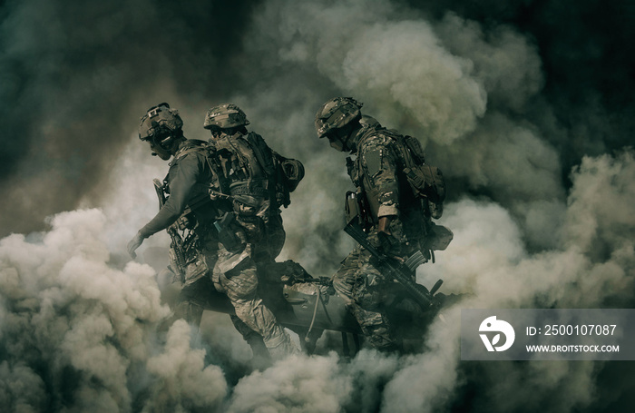 Army Soldiers carrying patient to the aircraft between smoke in the battle field